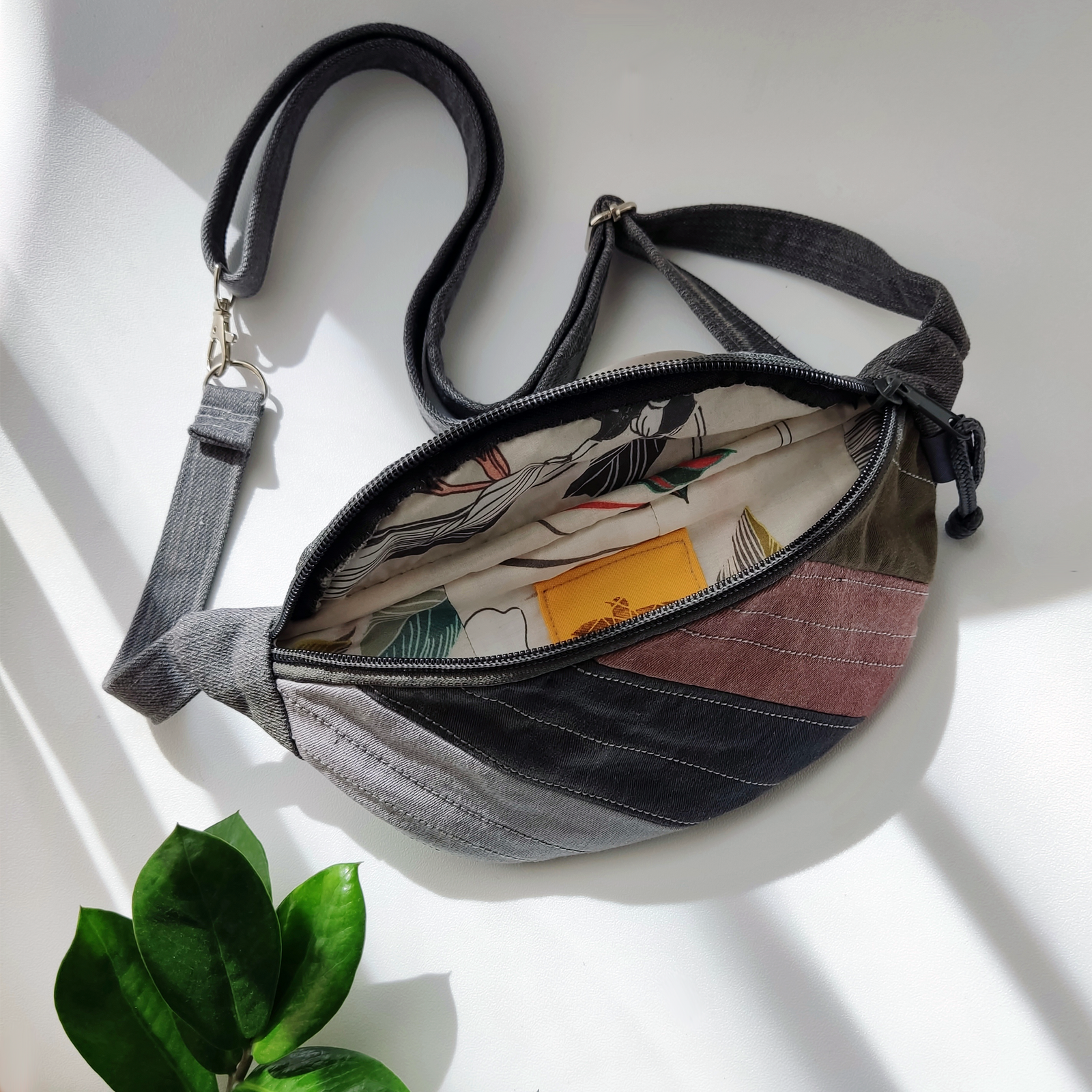 Inside view of a KOLLIB upcycled grey denim patchwork belt bag.