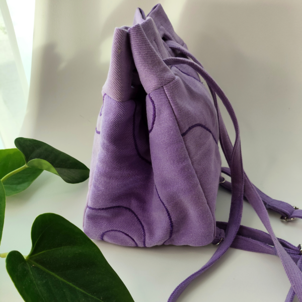 Side view of a KOLLIB purple upcycled denim bohemian style backpack.