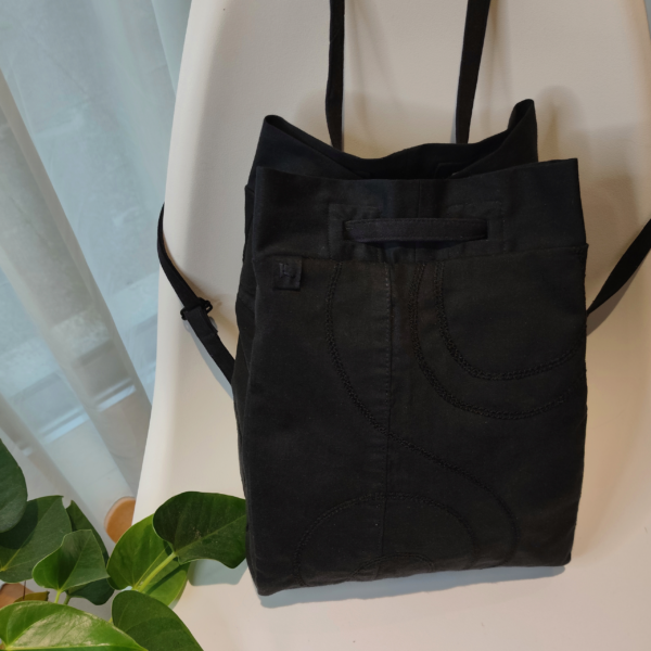 Front view of a KOLLIB black upcycled denim bohemian style backpack.